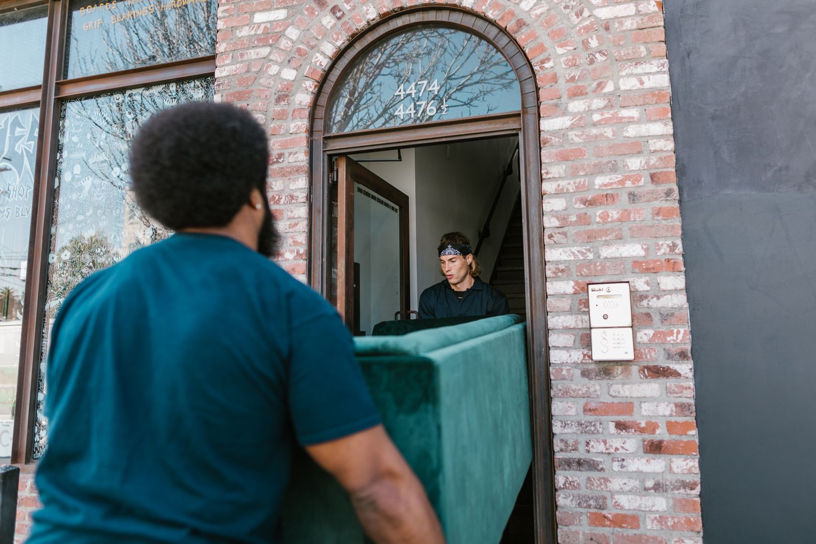 Two movers carrying a sofa through a front door
